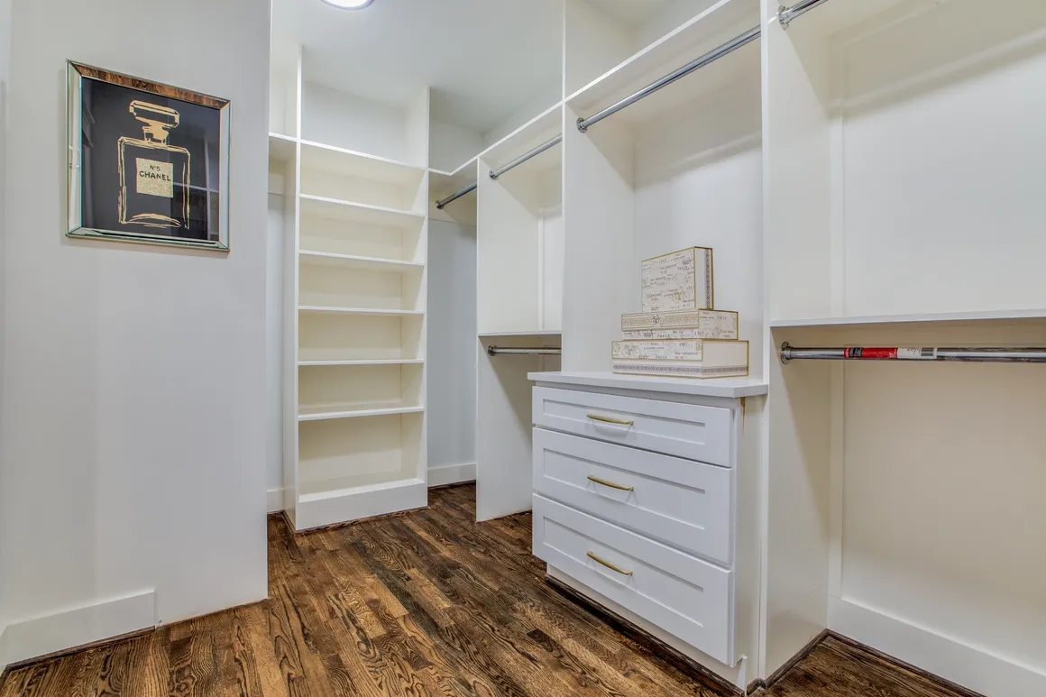 A white closet with many shelves and drawers.