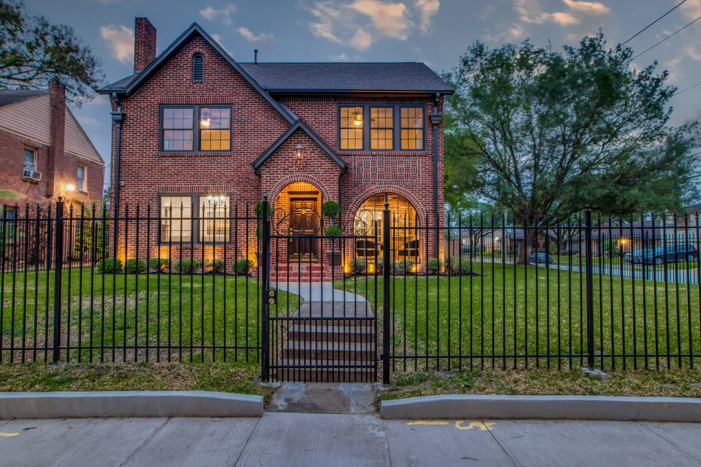A brick house with a metal fence and gate.