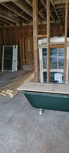 A bathroom being built with wood and green tub.