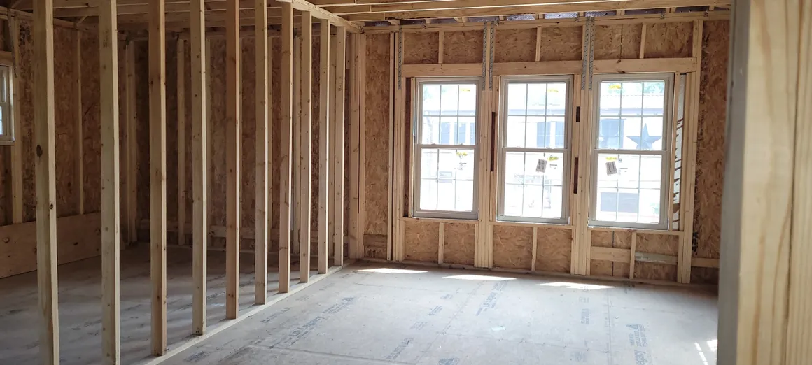 A room with two windows and some wooden frames.