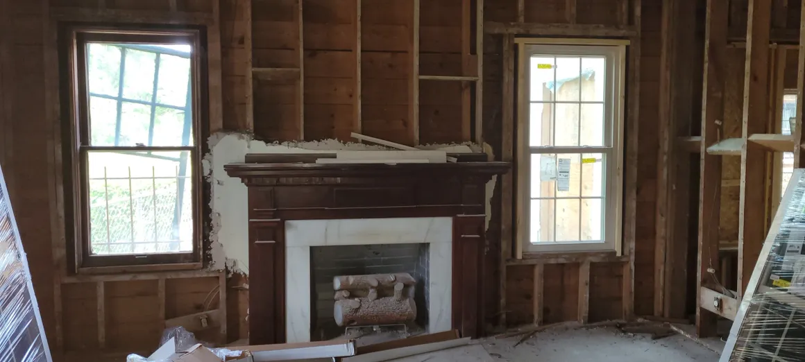 A fireplace in the middle of a room with wood paneling.