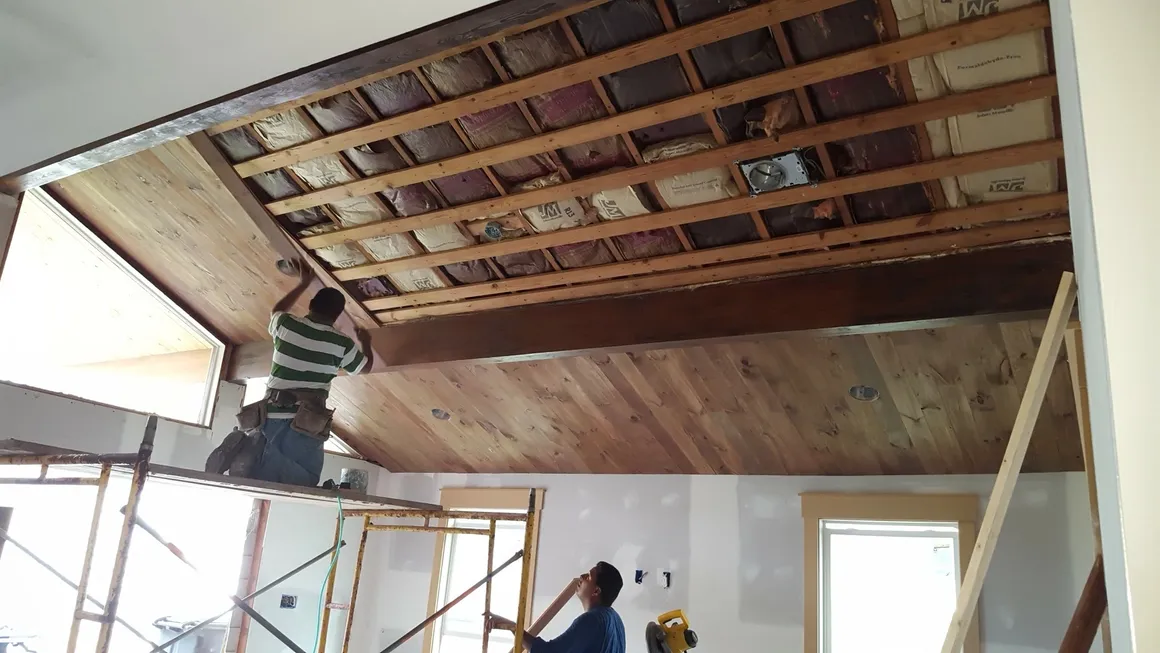 Two men working on a ceiling in the process of being installed.
