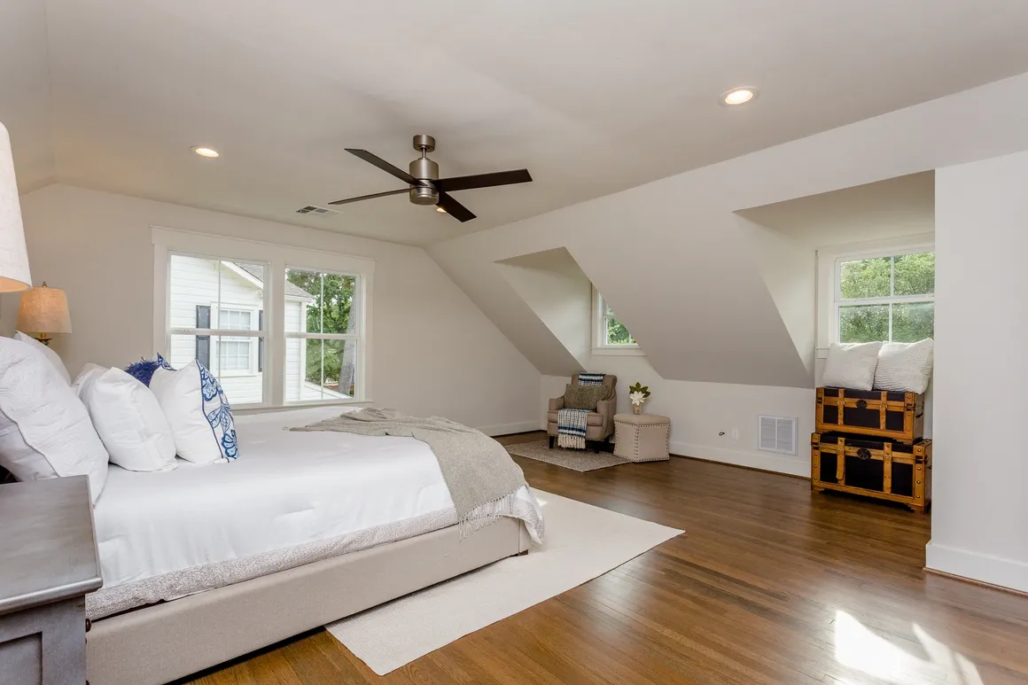 A bedroom with a large bed and wooden floors.